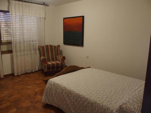 a bedroom with a bed and a chair and a window at Casa Grande de Borizu Playa in Celorio