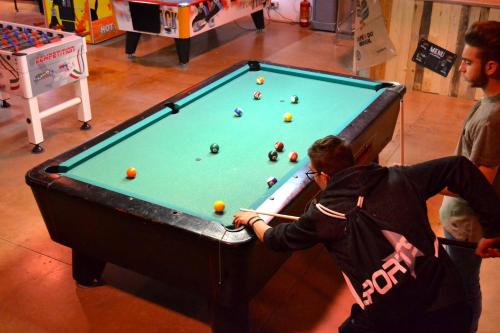 a woman playing a game of pool on a pool table at Ostello Salento in Alezio