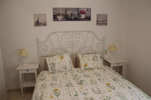 Apartamento Carihuela Beach & Sun في توريمولينوس: غرفة نوم بسرير ابيض مع طاولتين