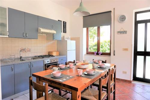 een keuken met een houten tafel met stoelen en een keuken met blauwe kasten bij Casa Lina in San Felice Circeo