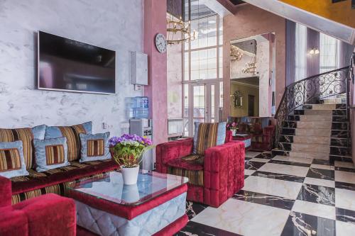 vestíbulo con sillas rojas, mesa y TV en Viktoria Hotel, en Samara
