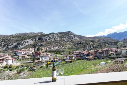 a bottle of wine sitting on a table in front of a village at La Giostra Home Apartments in Drena