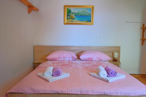 a pink bed with towels and pillows on it at Studio apartman Mia in Stobreč