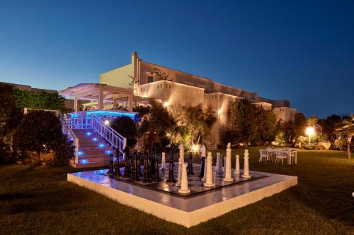 a building with a fountain in front of a house at night at Lagos Mare Hotel in Agios Prokopios