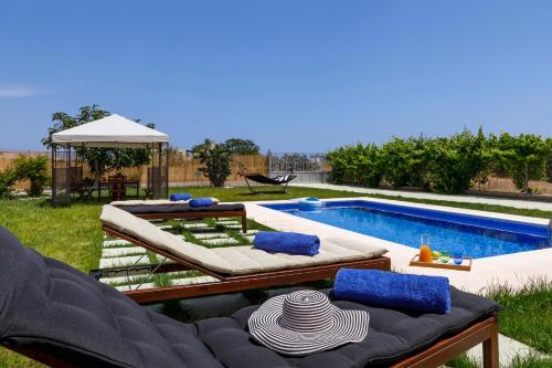 a backyard with a pool with two lounge chairs at Summer Breeze Villa in Afantou