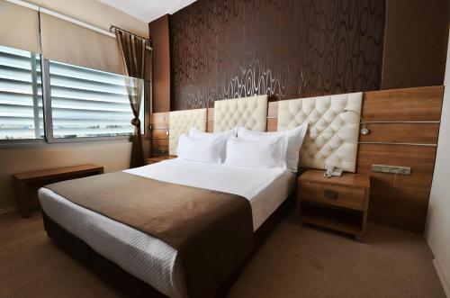 a bedroom with a large white bed and a window at Orty Airport Hotel in Izmir
