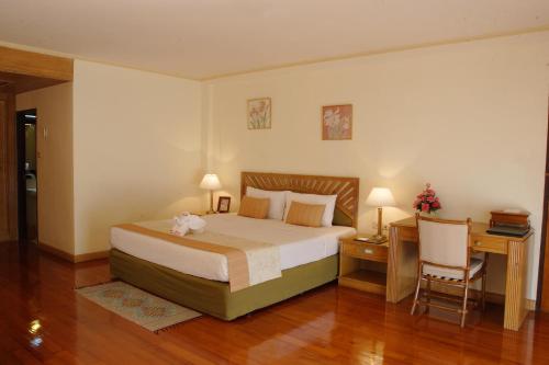 a bedroom with a bed and a desk and a chair at The Imperial Mae Hong Son Resort in Mae Hong Son