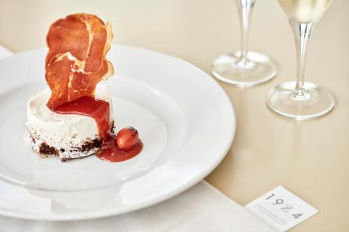 a piece of cake on a white plate on a table with glasses at Lagos Mare Hotel in Agios Prokopios