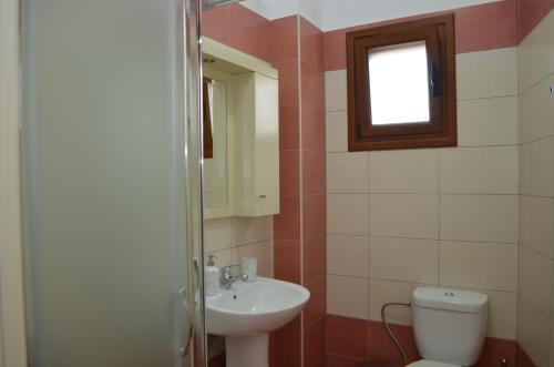 a bathroom with a sink and a toilet and a window at Saranda View Apartments in Sarandë