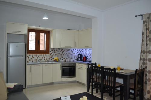 a kitchen with white cabinets and a table with chairs at Saranda View Apartments in Sarandë