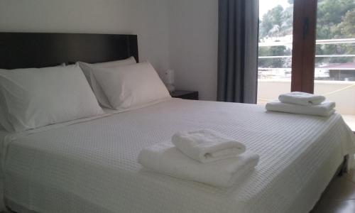 a white bed with towels on it with a window at Saranda View Apartments in Sarandë