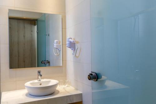 a bathroom with a sink and a mirror at Rodos Star Hotel in Afantou