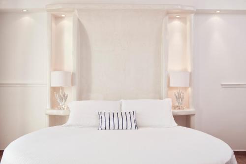 a white bedroom with a white bed with two windows at Lagos Mare Hotel in Agios Prokopios