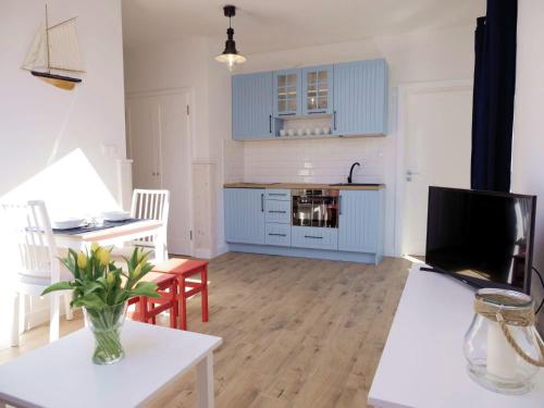 uma cozinha e sala de estar com armários azuis em Apartament Biały Żagiel em Rowy