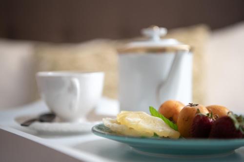 a plate of fruit on a table with a coffee cup at Porto Maltese Boutique Estate in Agios Nikolaos