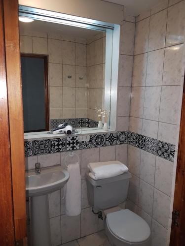 La salle de bains est pourvue de toilettes, d'un lavabo et d'un miroir. dans l'établissement Hotel 5 Norte, à Viña del Mar