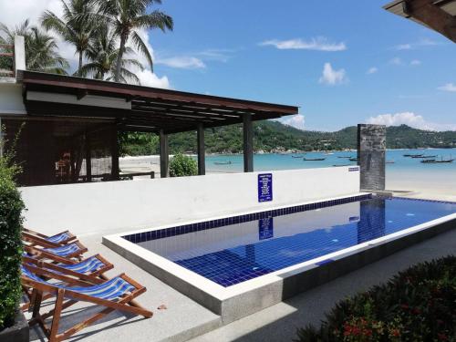 una piscina accanto a due sedie e una casa di Limelight Village a Thong Nai Pan Yai