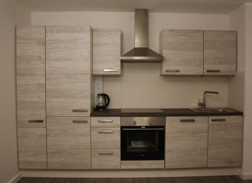 a kitchen with wooden cabinets and a stove at Die Stadtwohnung in Stadthagen