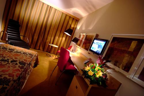 a hotel room with a bed and a desk with a television at Hotel HP Park Poznań Malta in Poznań