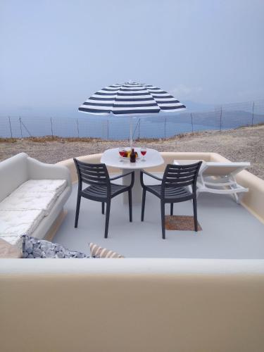 a table and chairs under an umbrella on the beach at Santa Rinoula Suites Sea Sunset views Adults only in Megalokhori