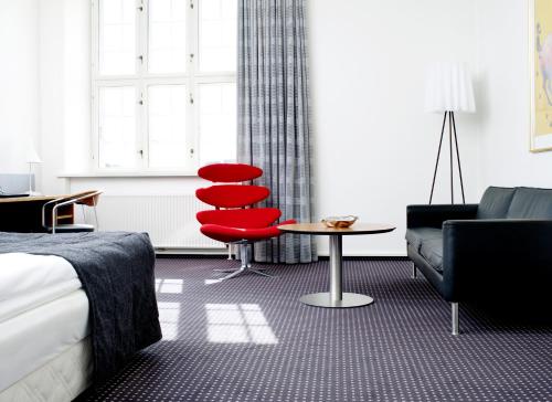 a hotel room with a red chair and a couch at Hotel Koldingfjord in Kolding