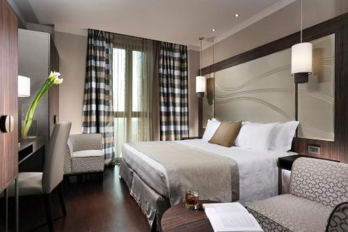 a hotel room with a bed and a desk and chairs at Uptown Palace in Milan