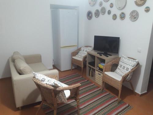ein Wohnzimmer mit einem Sofa, einem TV und Stühlen in der Unterkunft Casa do Beco do Beiçudo centro de Evora in Évora