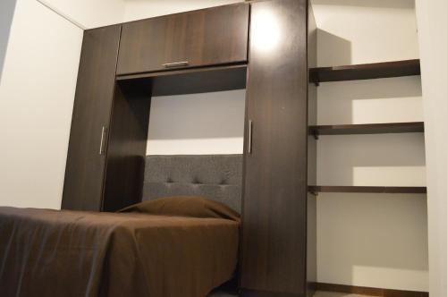 a bedroom with a large wooden cabinet with shelves at Apartaestudio San Nicolas in Popayan