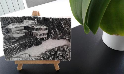 a painting of a building on a stand next to a plant at Apartment VILLA MERCI in Sarajevo
