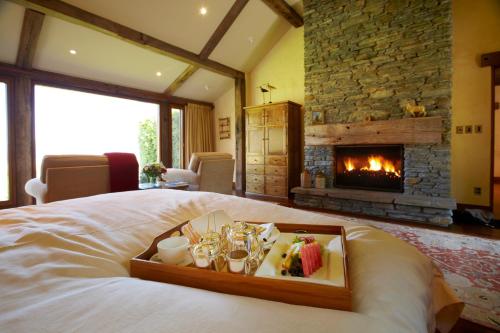 a tray of food on a bed with a fireplace at Blanket Bay in Glenorchy