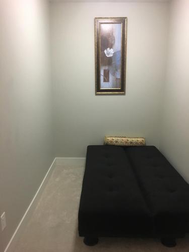 Un dormitorio con una cama negra y una foto en la pared en Waterscapes Appartment, en Kelowna