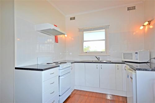 a white kitchen with white appliances and a window at Breakers 4 2 Hill Street in Port Macquarie