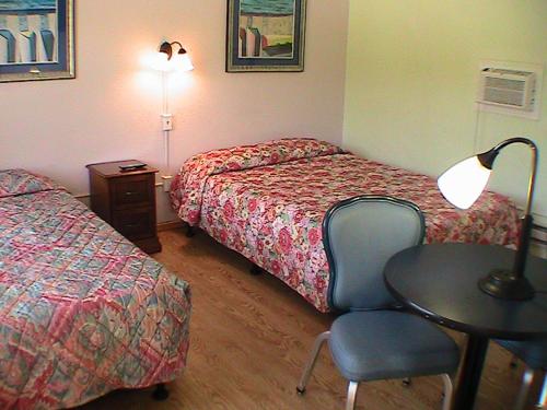 a hotel room with two beds and a table and a chair at At Home Express Tangerine Inn in DeLand