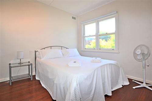 a bedroom with a white bed with a fan and a window at Breakers 6 2 Hill Street in Port Macquarie