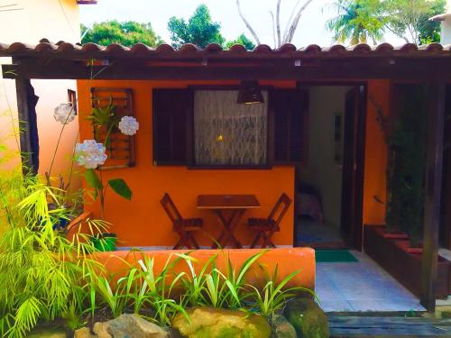 een oranje huis met een tafel en stoelen bij Flat aluguel Abraão 2,Ilha Grande in Abraão