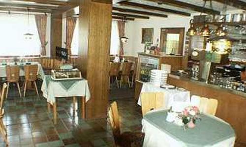 a restaurant with white tables and chairs and a kitchen at Landgasthof Restaurant Laibach in Bad Berleburg