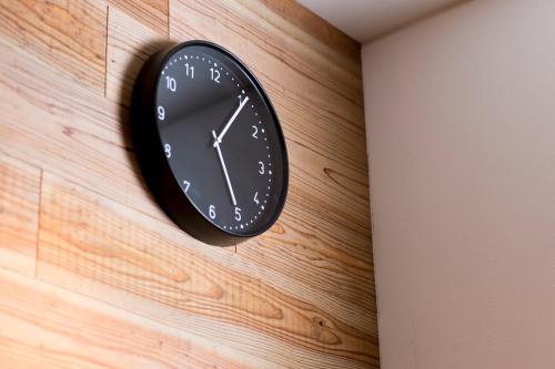 a black clock hanging on a wooden wall at Sano-san-chi in Izumi-Sano