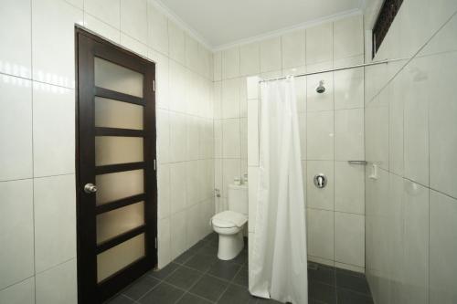a bathroom with a toilet and a shower with a shower curtain at Swastika Bungalows in Sanur