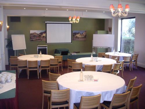 a conference room with tables and chairs and a screen at Best Western Plus The Tudor Box Hill in Box Hill