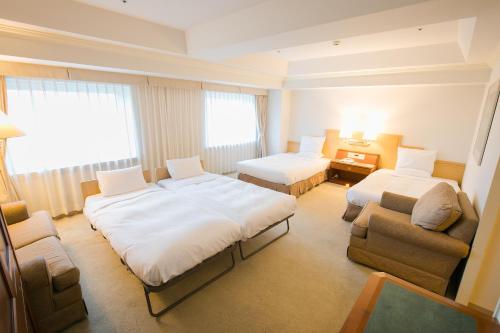 a hotel room with two beds and a chair at HOTEL MYSTAYS PREMIER Sapporo Park in Sapporo
