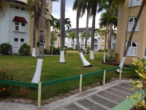 a park in front of a building with palm trees at Almond Grove at Sand Castle in Ocho Rios