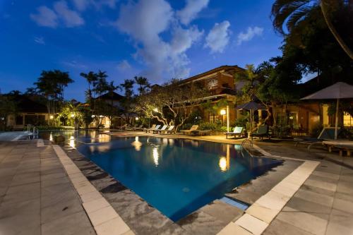 a swimming pool in a resort at night at Bumi Ayu Bungalow Sanur in Sanur