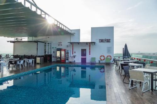 a pool on the roof of a building with tables and chairs at Amerin Hotel Johor Bahru in Johor Bahru