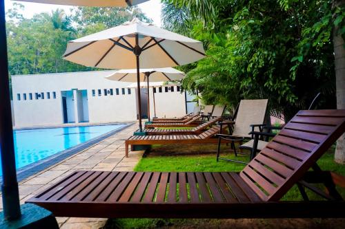 a group of chairs and an umbrella next to a pool at Lavendish Okrin Hotel in Kataragama
