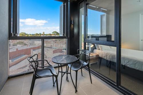 a balcony with a table and chairs and a bed at Anchorage Apartments Hampton in Melbourne