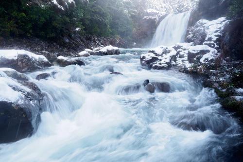 a waterfall with snow on top of the rocks and water at Alpine Chalets in National Park