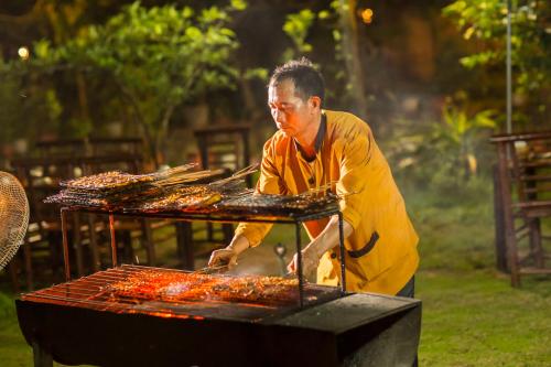 寧平的住宿－三谷稻田度假村，一个人在烧烤架上做饭