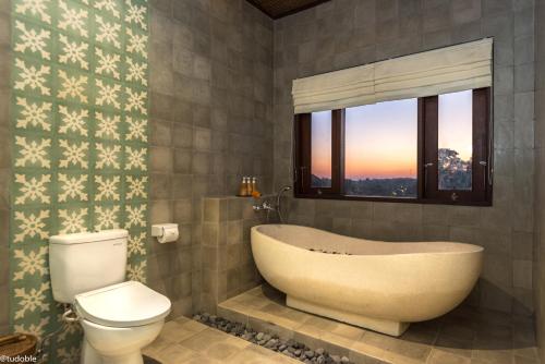 a bathroom with a tub and a toilet and a window at Bliss Ubud Abangan in Ubud