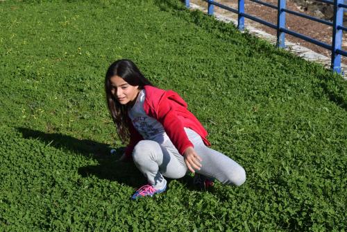 a young girl is sitting on the grass at Lydia Rooms & Studios in Preveza