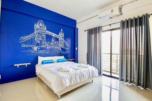 a blue bedroom with a bed and a blue wall at PJ Loft Hotel in Ban Khok Krathin
